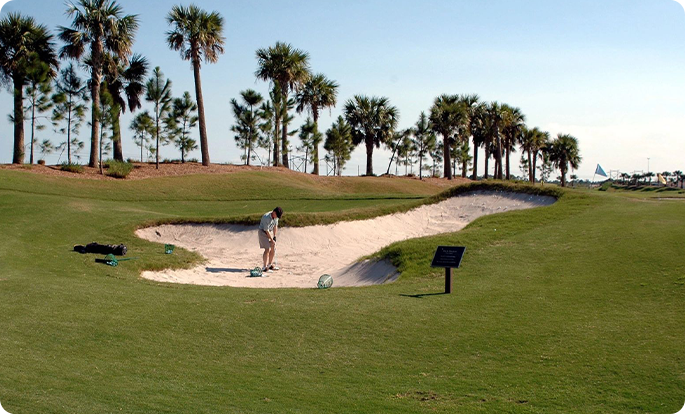 A man is playing golf on the sand.