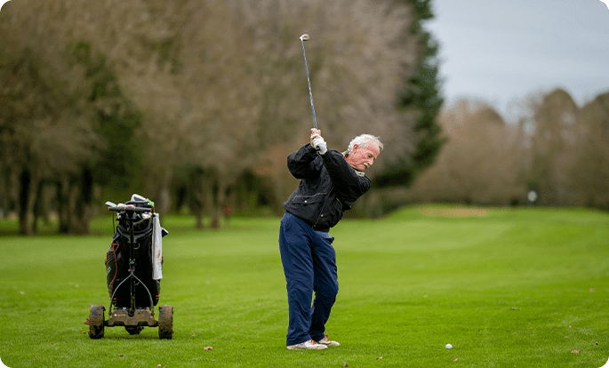 A man swinging at the golf ball on a green.