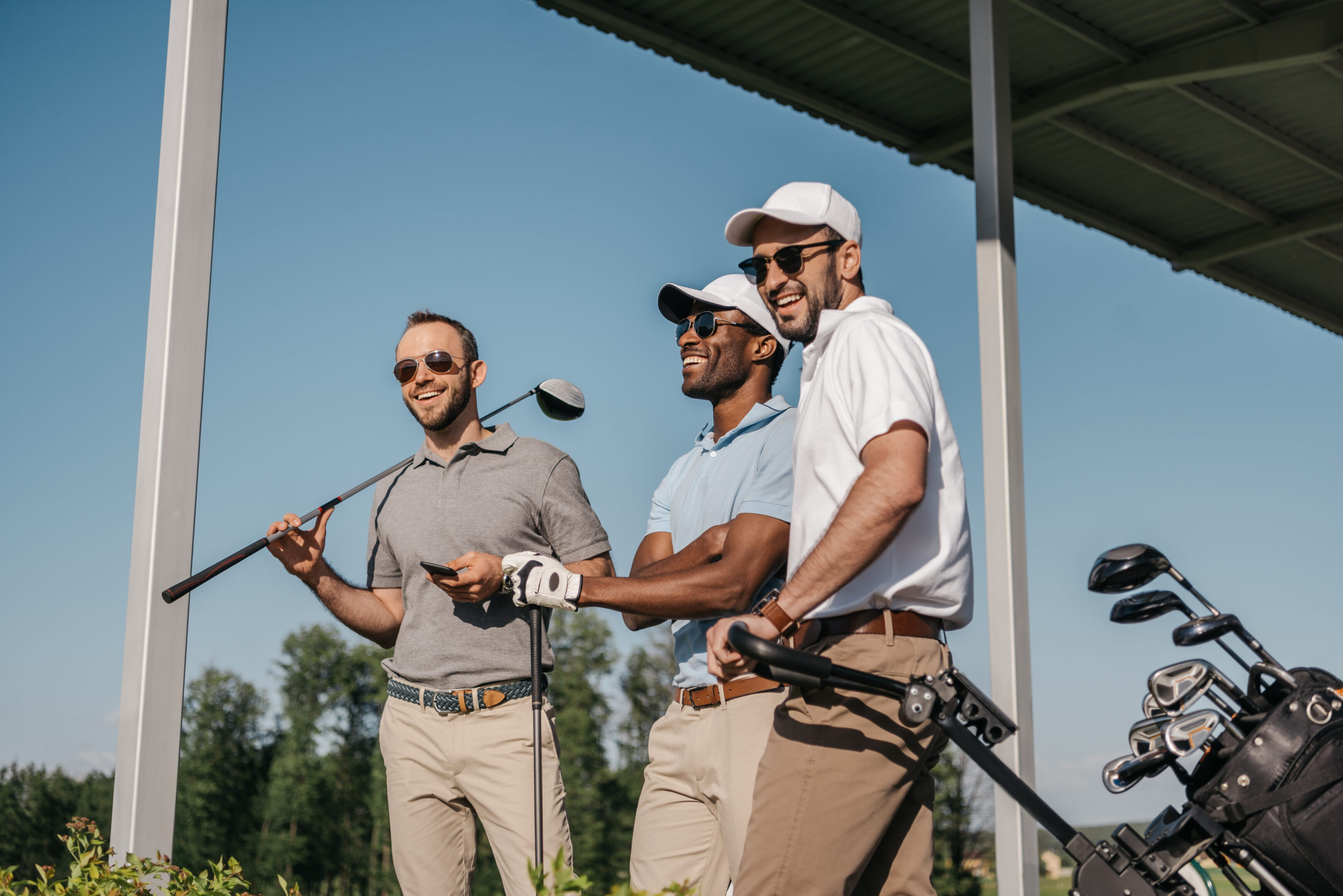 Three men are playing golf on a sunny day.